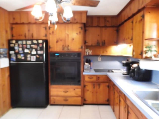 kitchen with black appliances, a chandelier, brown cabinets, light tile patterned floors, and light countertops