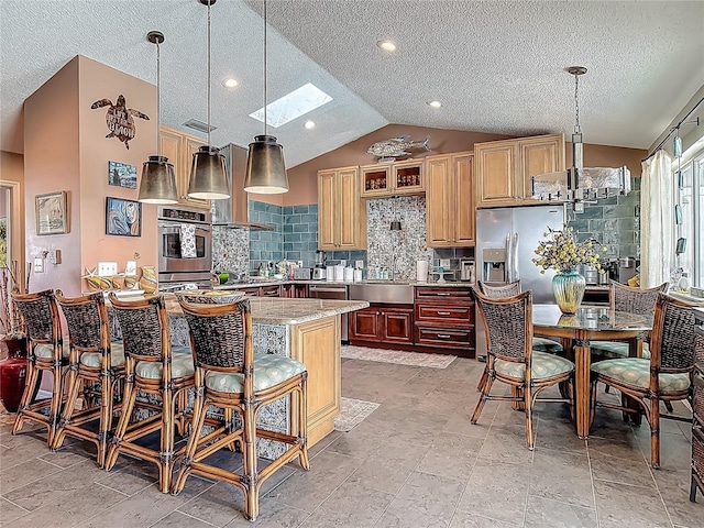 31 Sea Harbor Dr E, Ormond Beach, FL 32176 - kitchen featuring a skylight, appliances with stainless steel finishes, lofted ceiling, a textured ceiling, and wall chimney exhaust hood