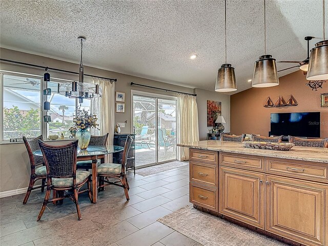 31 Sea Harbor Dr E, Ormond Beach, FL 32176 - kitchen with brown cabinetry, a textured ceiling, hanging light fixtures, and light stone counters