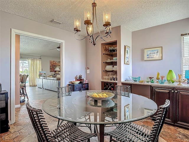 31 Sea Harbor Dr E, Ormond Beach, FL 32176 - dining area with a textured ceiling, ceiling fan, a chandelier, and light stone finish flooring