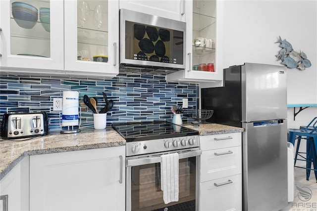 3509 S Atlantic Ave Unit 102And 103, New Smyrna Beach, FL 32169 - kitchen featuring stainless steel appliances, white cabinetry, glass insert cabinets, light stone countertops, and backsplash