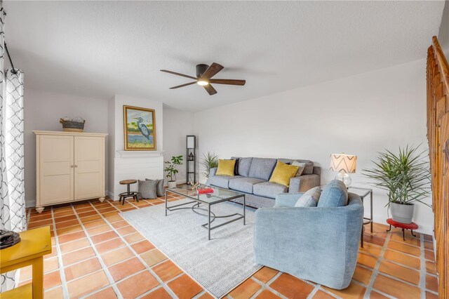 living room featuring ceiling fan, a textured ceiling, baseboards, and light tile patterned floors