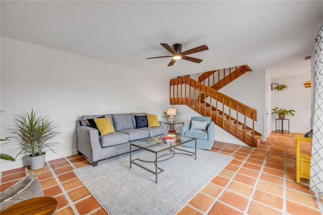 tiled living room with ceiling fan and stairs