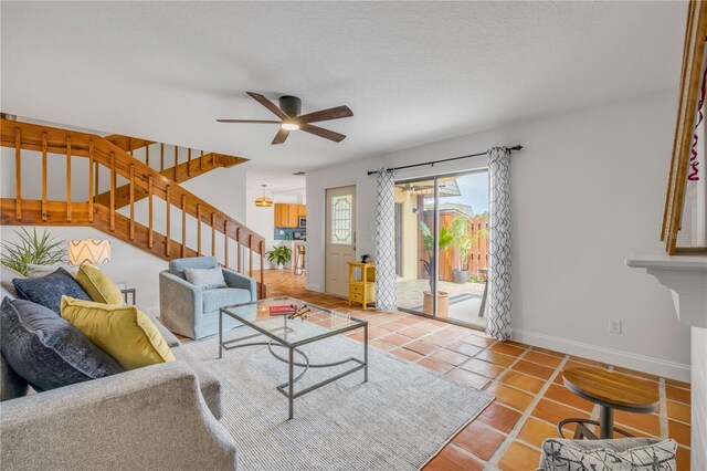 living room featuring baseboards, stairs, tile patterned floors, and ceiling fan