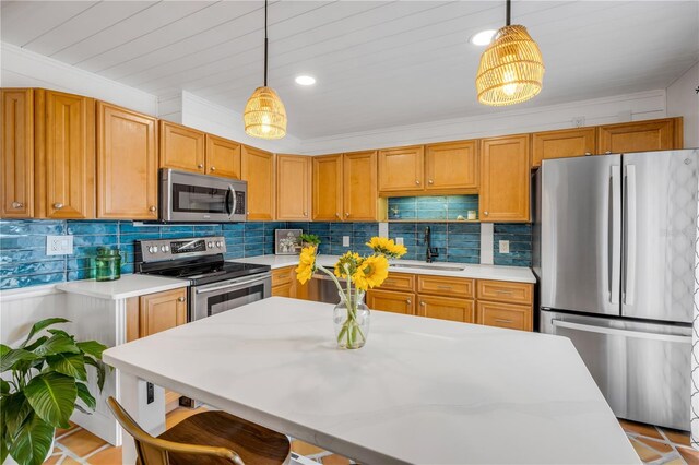 kitchen with appliances with stainless steel finishes, a sink, light countertops, hanging light fixtures, and backsplash
