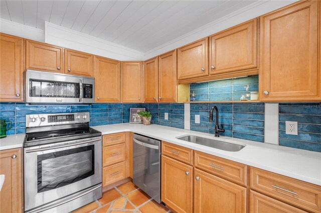 kitchen with stainless steel appliances, a sink, light countertops, and ornamental molding