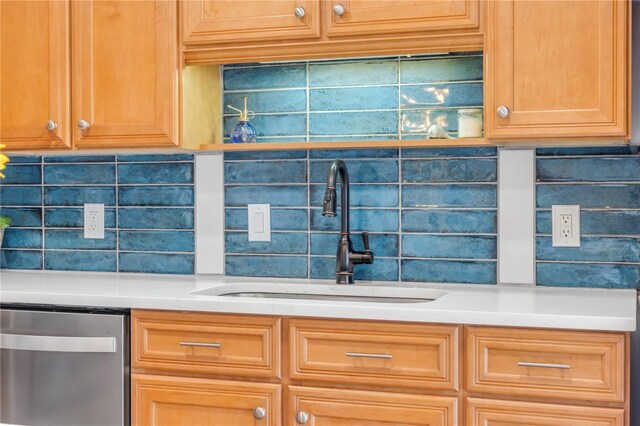 kitchen featuring stainless steel dishwasher, a sink, decorative backsplash, and light countertops