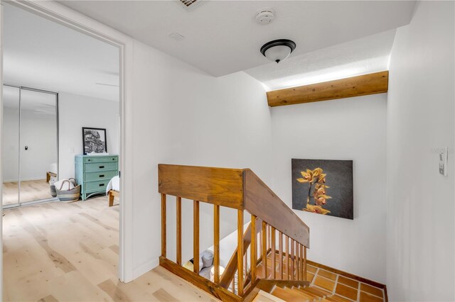 hall featuring an upstairs landing and baseboards