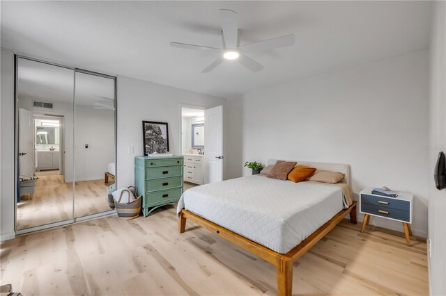 bedroom with light wood-type flooring, ensuite bath, and a closet