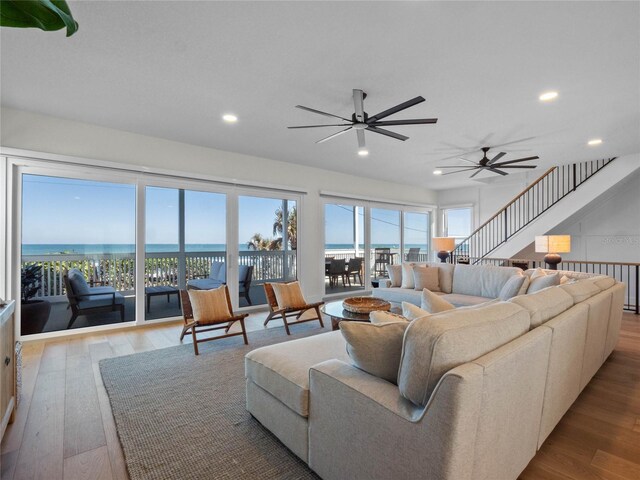 living area with ceiling fan, wood finished floors, recessed lighting, and a water view