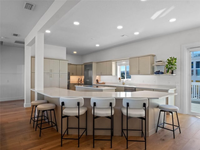 kitchen featuring a large island, open shelves, light wood-style flooring, stainless steel dishwasher, and recessed lighting