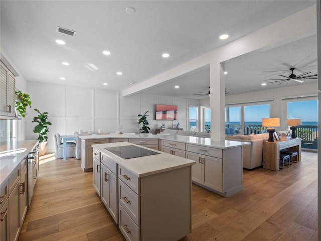 kitchen featuring a center island, ceiling fan, black electric cooktop, gray cabinets, and recessed lighting