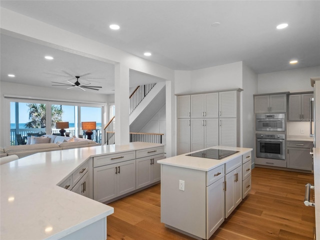kitchen featuring black electric stovetop, a kitchen island, light wood finished floors, a ceiling fan, and recessed lighting