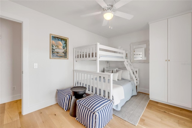 bedroom with light wood-style flooring, baseboards, and a ceiling fan