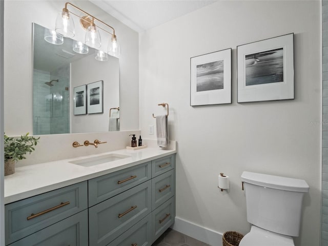 bathroom featuring tiled shower, toilet, vanity, baseboards, and tile patterned flooring
