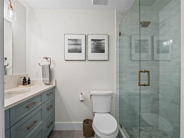 bathroom with a shower stall, tile patterned floors, toilet, vanity, and baseboards