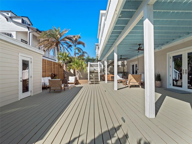 wooden terrace with french doors, outdoor lounge area, a ceiling fan, fence, and stairway
