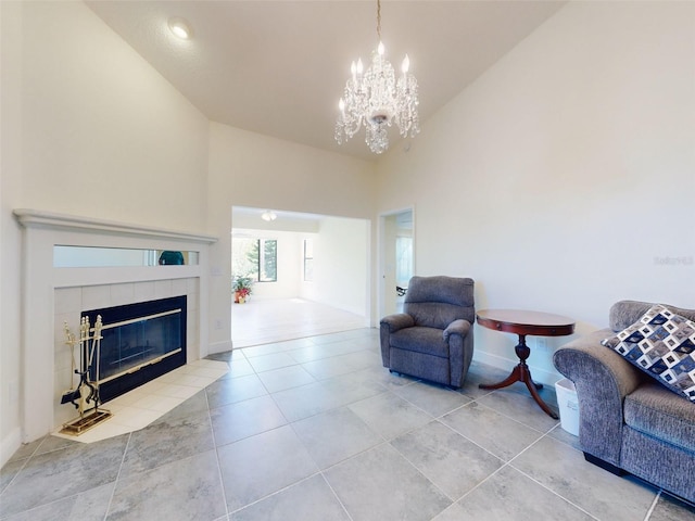tiled living room featuring high vaulted ceiling, a chandelier, baseboards, and a tile fireplace
