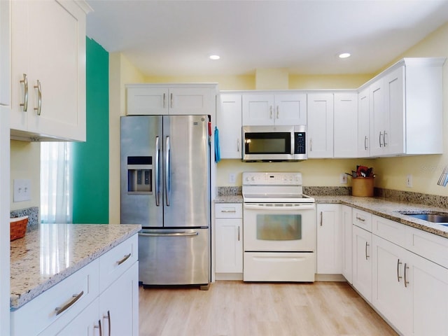 kitchen featuring stainless steel appliances, white cabinetry, a sink, light wood-style floors, and recessed lighting