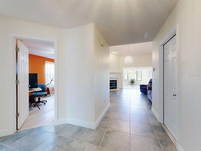 hallway featuring an office area, a chandelier, healthy amount of natural light, light tile patterned flooring, and a textured ceiling