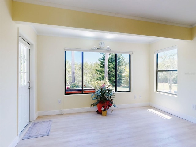 entrance foyer with wood finished floors, crown molding, and baseboards