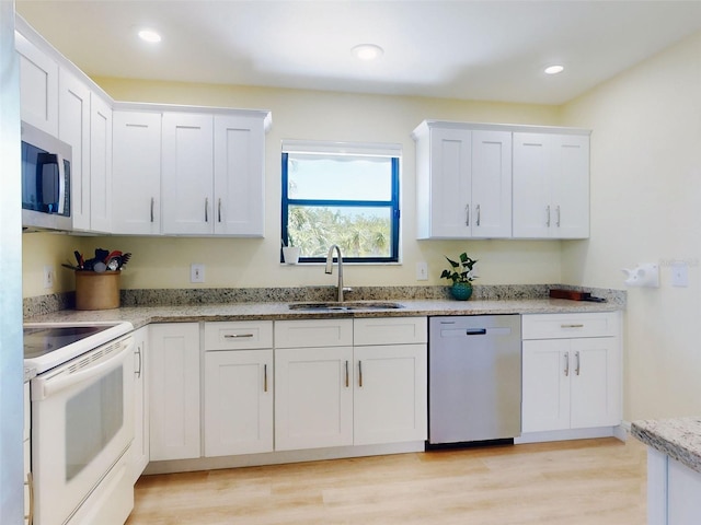 kitchen featuring stainless steel appliances, a sink, white cabinetry, light stone counters, and recessed lighting