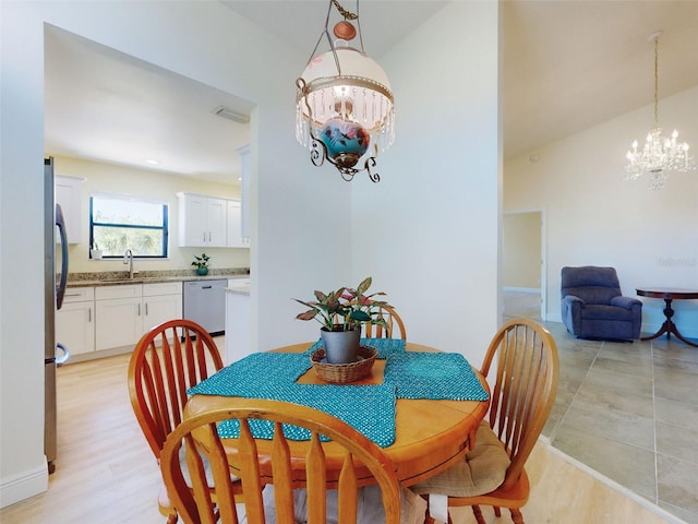 dining space with a chandelier, baseboards, high vaulted ceiling, and light wood-style flooring