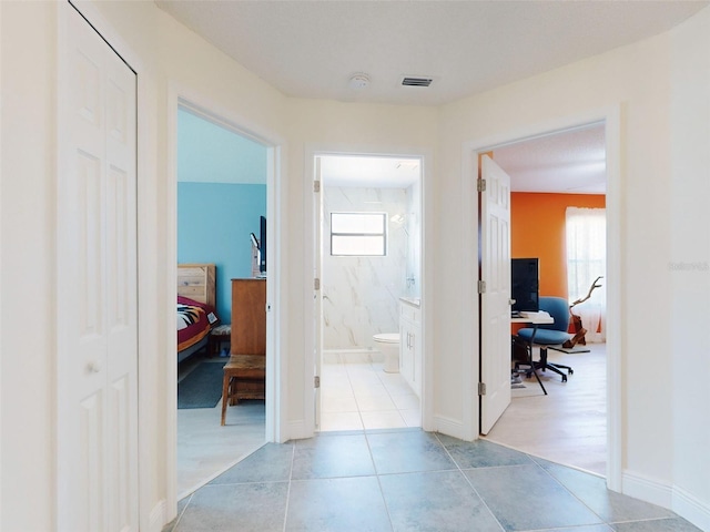 hallway featuring healthy amount of natural light, a desk, and tile patterned flooring