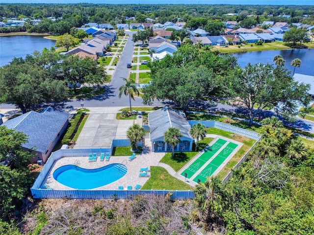 aerial perspective of suburban area featuring a pool area and a nearby body of water