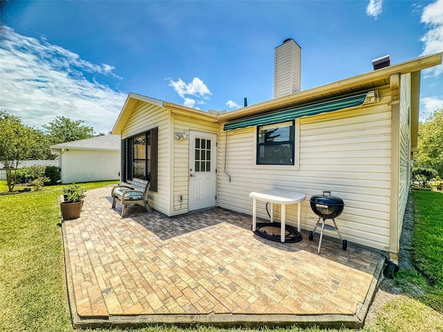 back of house featuring a patio area, a yard, and a chimney