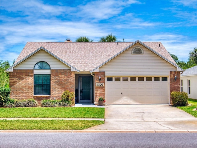 ranch-style house with brick siding, concrete driveway, a garage, a front yard, and roof with shingles