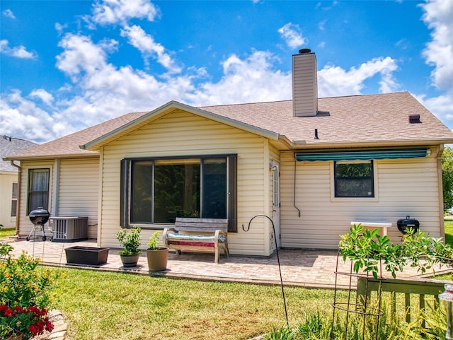 back of house featuring a patio area, a lawn, a chimney, central air condition unit, and roof with shingles