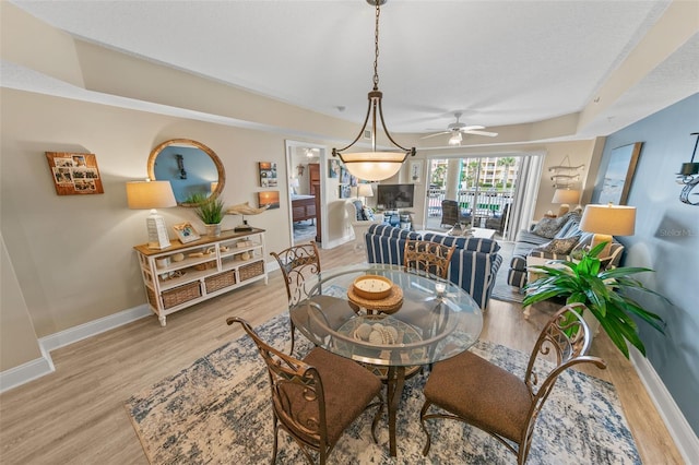 dining space with light wood finished floors, baseboards, and a ceiling fan