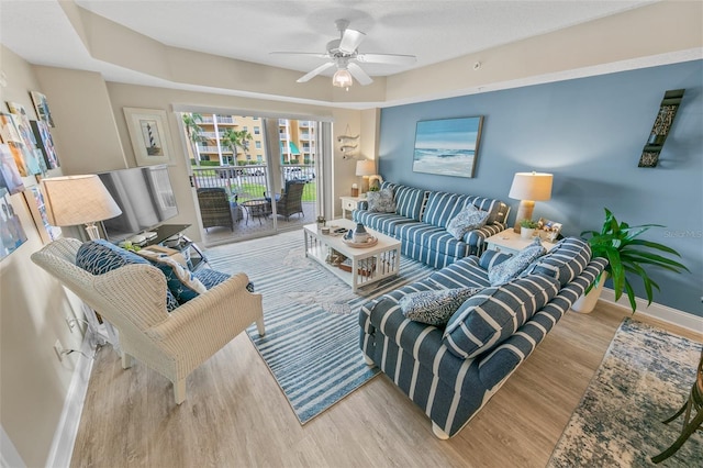 living room featuring wood finished floors, baseboards, and ceiling fan
