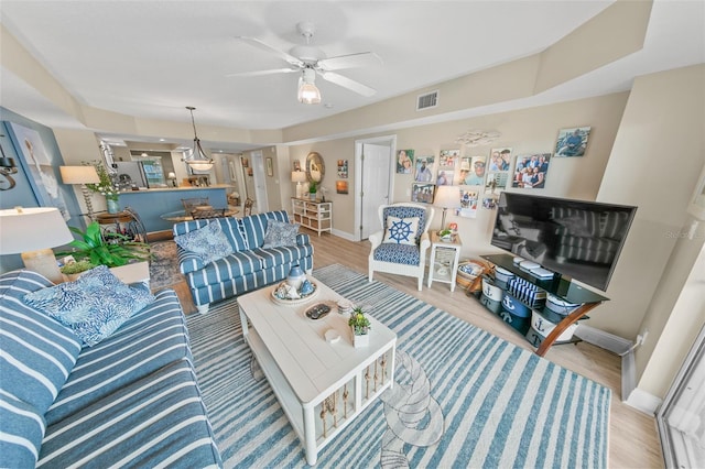 living area with baseboards, wood finished floors, and ceiling fan
