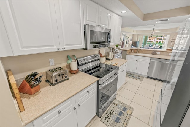 kitchen featuring appliances with stainless steel finishes, white cabinets, light tile patterned floors, recessed lighting, and a sink
