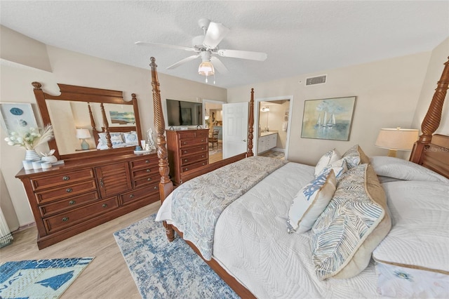 bedroom with wood finished floors, ensuite bath, a textured ceiling, and a ceiling fan
