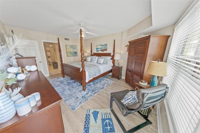 bedroom with light wood-style floors, a ceiling fan, and ensuite bath