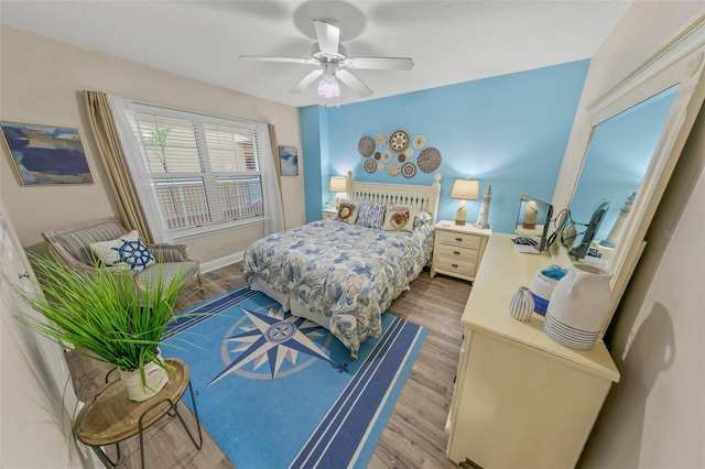 bedroom featuring light wood finished floors, a ceiling fan, and baseboards