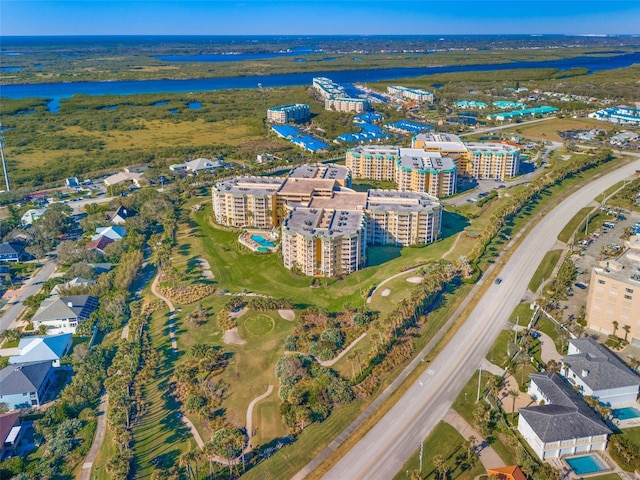 aerial view of property and surrounding area featuring a large body of water, apartment complex, and a golf course