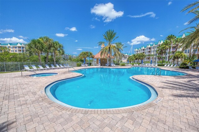community pool with a patio, fence, and a community hot tub