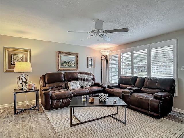 living room featuring light wood finished floors, a ceiling fan, a textured ceiling, and baseboards