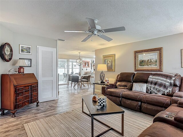 living room with ceiling fan, wood finished floors, and a textured ceiling
