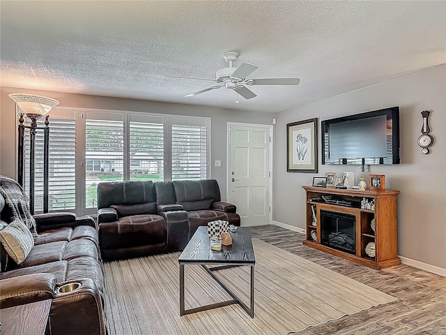 living room featuring a ceiling fan, wood finished floors, a textured ceiling, and baseboards
