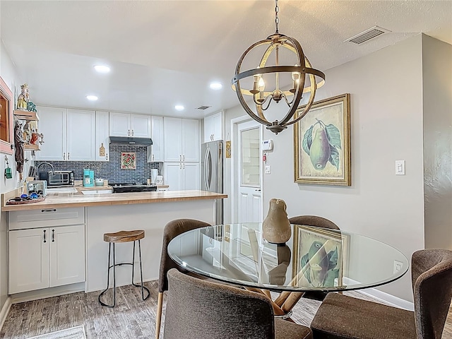 kitchen featuring a chandelier, a peninsula, light wood-style flooring, light countertops, and white cabinetry