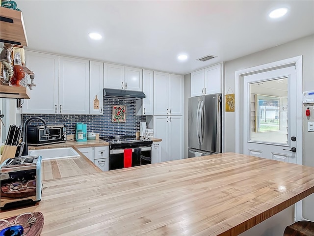 kitchen with freestanding refrigerator, electric stove, white cabinets, under cabinet range hood, and decorative backsplash