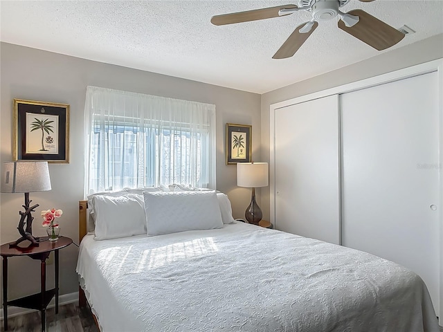 bedroom with a textured ceiling, a closet, ceiling fan, and wood finished floors