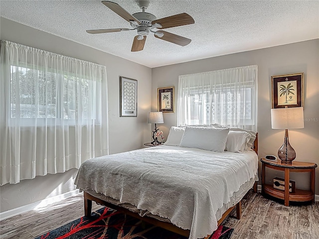 bedroom featuring wood finished floors, a textured ceiling, a ceiling fan, and baseboards