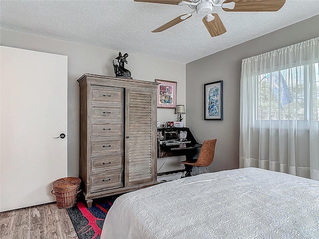 bedroom featuring wood finished floors, a textured ceiling, and a ceiling fan