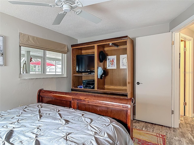 bedroom featuring wood finished floors, a textured ceiling, and a ceiling fan